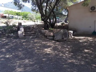 a tree and some rocks next to a building at gite tomasini sabrina zirilla in Monacia-dʼAullène