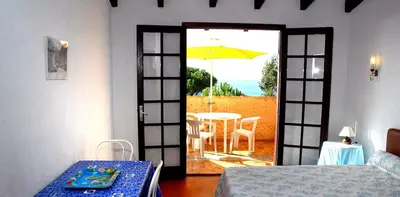 a room with a door open to a table with an umbrella at Motel Logis d'Abartello in Olmeto