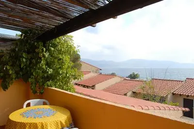 a yellow table on a balcony with a view of roofs at Motel Logis d'Abartello in Olmeto