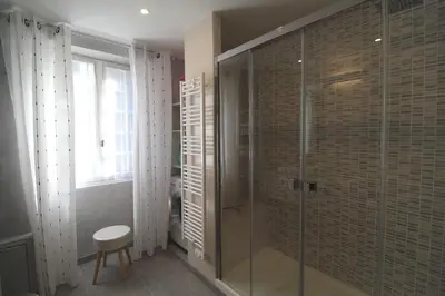 a bathroom with a glass shower with a stool at VILLA SANTINE AVEC TERRASSES et VUE PANORAMIQUE meublé tourisme 4 étoiles in Santa-Lucia-di-Tallano
