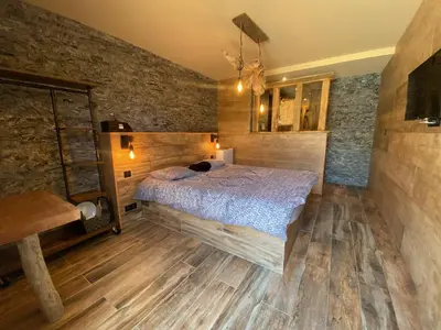 a bedroom with a bed and a stone wall at Chambres du Gozzi in Afa