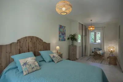 a bedroom with a blue bed with a wooden headboard at MAISONS BORD DE MER- MARINE DE SORBO - Gîtes 3 épis in Pinarellu