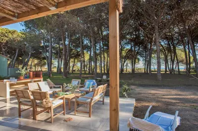 a patio with a table and chairs and trees at MAISONS BORD DE MER- MARINE DE SORBO - Gîtes 3 épis in Pinarellu