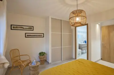 a bedroom with a yellow bed and a chandelier at MAISONS BORD DE MER- MARINE DE SORBO - Gîtes 3 épis in Pinarellu