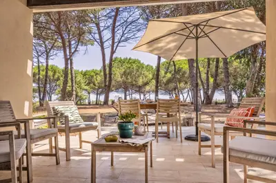 a patio with tables and chairs and an umbrella at MAISONS BORD DE MER- MARINE DE SORBO - Gîtes 3 épis in Pinarellu