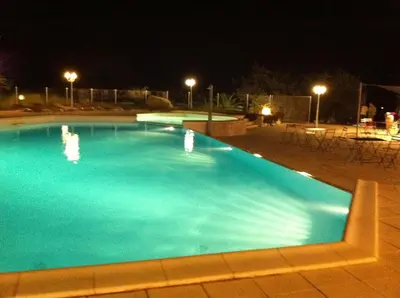 a large blue swimming pool at night at Residence Ribellinu in Pianottoli-Caldarello