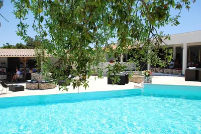 a swimming pool with a tree in front of a building at Residence Ribellinu in Pianottoli-Caldarello