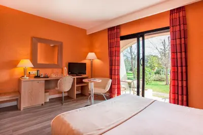 a hotel room with a bed and a desk and a window at Chez Walter in Lucciana