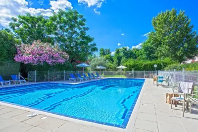a swimming pool with chairs and umbrellas at Chez Walter in Lucciana