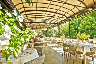 a restaurant with white tables and chairs and plants at Chez Walter in Lucciana
