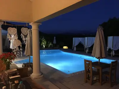 a swimming pool at night with a table and umbrellas at Villa Torrella in Mezzavia
