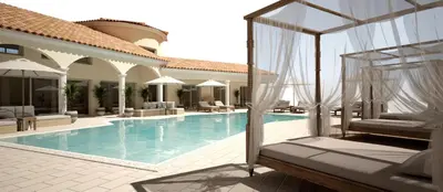 a swimming pool with chairs and umbrellas next to a house at Villa Torrella in Mezzavia