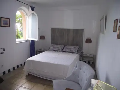 a bedroom with a bed and a chair and a window at soleil et farniente in Cervione