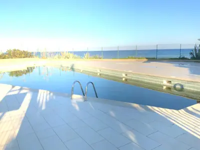 a swimming pool with the beach in the background at Studio Bord De Mer in Santa-Lucia-di-Moriani