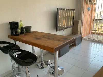 a kitchen with a wooden table and two bar stools at Studio Bord De Mer in Santa-Lucia-di-Moriani