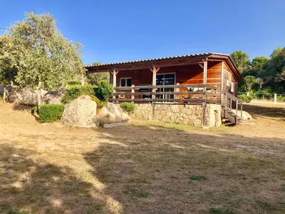 a log cabin with a porch and a stone wall at A Casetta in Pianottoli-Caldarello
