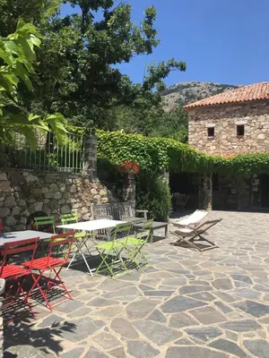 a patio with chairs and tables and a building at A Muvrella in Pioggiola