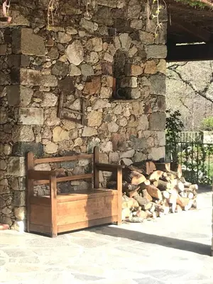a wooden bench sitting in front of a stone wall at A Muvrella in Pioggiola