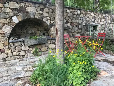 a stone wall with two red chairs and flowers at A Muvrella in Pioggiola