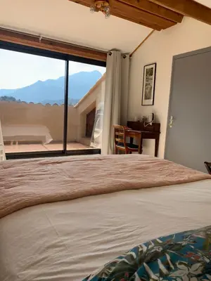 a bedroom with a bed and a large window at A Muvrella in Pioggiola