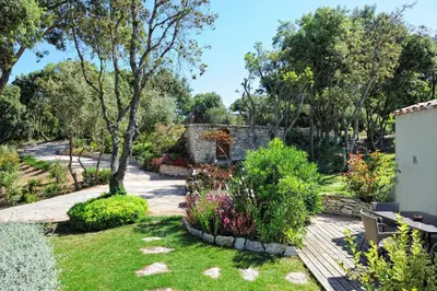 a garden with flowers and a wooden deck at Résidence Sophia in Bonifacio