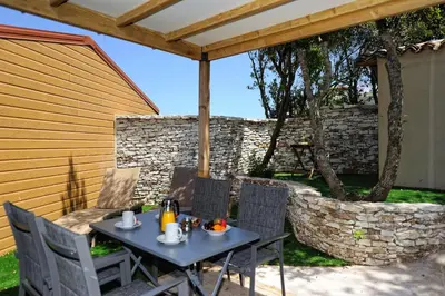 a table and chairs on a patio with a stone wall at Résidence Sophia in Bonifacio