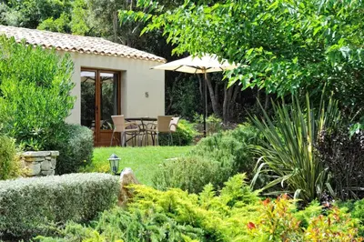 a garden with a table and an umbrella at Résidence Sophia in Bonifacio