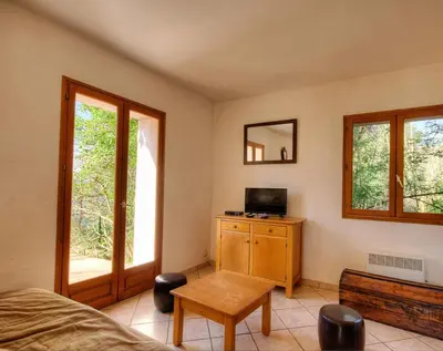 a bedroom with a bed and a table and windows at A Pivarella in Grosseto-Prugna