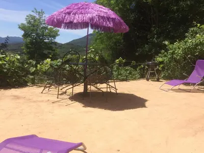 a purple umbrella and chairs in the sand at A Pivarella in Grosseto-Prugna