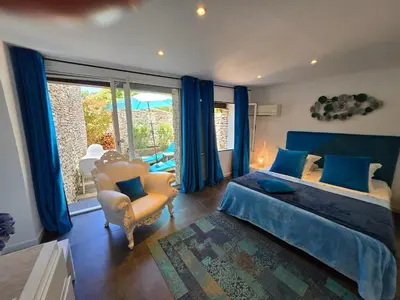 a bedroom with a bed and a chair and a window at Villa Petra Bianca Suites & Chambres in Bonifacio