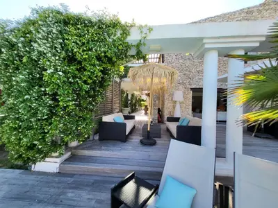 a patio with couches and chairs and a hedge at Villa Petra Bianca Suites & Chambres in Bonifacio