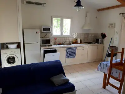 a kitchen with a blue couch in a room at Mini Villa à 100m de la mer avec prise de recharge élec privative in Sari Solenzara