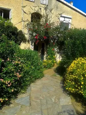 a stone path in front of a building with flowers at Maison du bonheur in Borgo