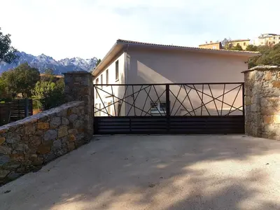 a garage with a gate and a stone wall at Pianotolu - Rez de villa entre mer et montagne in Moltifao