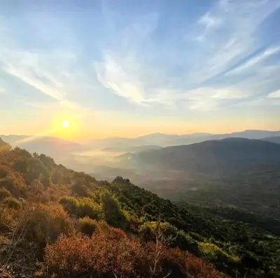 a view of a valley with the sun setting over the mountains at Pianotolu - Rez de villa entre mer et montagne in Moltifao