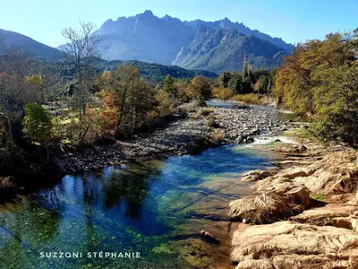 a river with rocks and mountains in the background at Pianotolu - Rez de villa entre mer et montagne in Moltifao