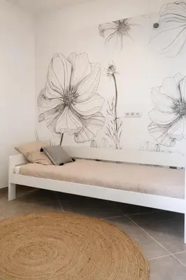 a bedroom with a bed with flowers on the wall at Pianotolu - Rez de villa entre mer et montagne in Moltifao