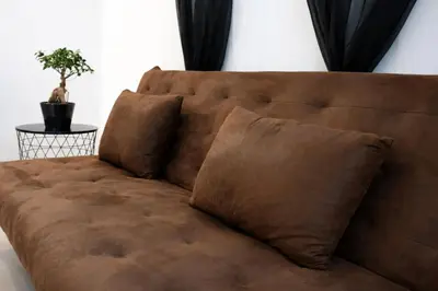 a brown couch with two pillows in a room at Pianotolu - Rez de villa entre mer et montagne in Moltifao