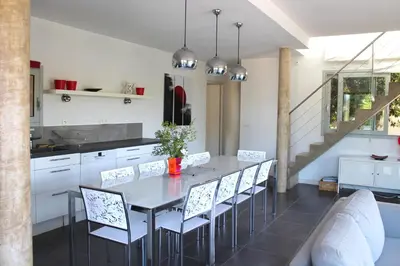 a kitchen with a dining room table and chairs at Les Hauts de la Testa in Sainte-Lucie de Porto-Vecchio