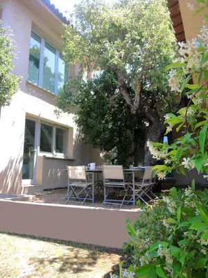 a patio with a table and chairs under a tree at Les Hauts de la Testa in Sainte-Lucie de Porto-Vecchio