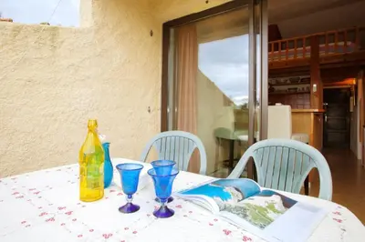 a table with a bottle and glasses and a book at Porticcio Terra Bella in Porticcio