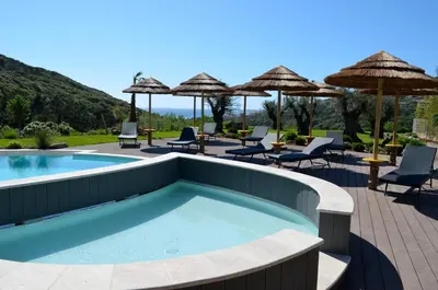 a swimming pool with chairs and umbrellas at Résidence de Tourisme Mare e Macchia in Tizzano