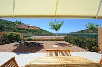 a patio with a table and an umbrella and chairs at Résidence de Tourisme Mare e Macchia in Tizzano