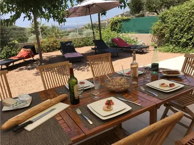a wooden table with plates of food and bottles of wine at Résidence de Tourisme Mare e Macchia in Tizzano