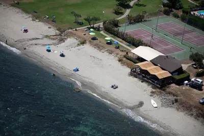 an aerial view of a beach with umbrellas and a tennis court at Orizonte in Cervione