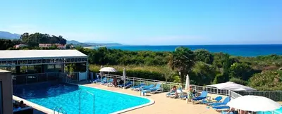 a resort with a swimming pool and chairs and the ocean at Orizonte in Cervione