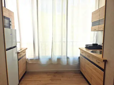 a kitchen with a large window with white curtains at Hôtel le Colibri in Lucciana