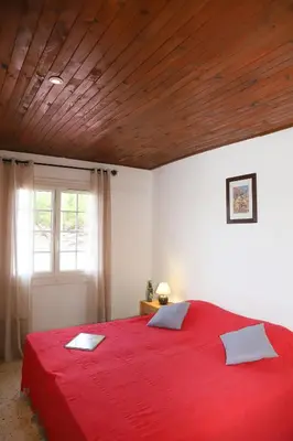 a bedroom with a red bed with a wooden ceiling at A Rossa Location in Favone