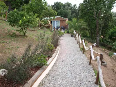 a garden path with wooden railings in a yard at Le petit chalet in Porticcio