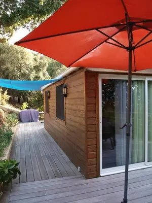 a large red umbrella sitting on a wooden deck at Le petit chalet in Porticcio